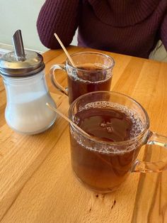 two mugs of tea sit on a wooden table