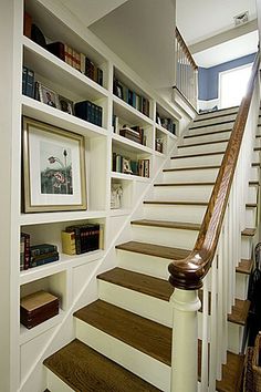 a staircase with bookshelves and pictures on the wall