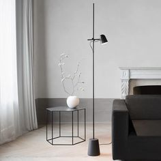 a living room with a black couch and white vase on the table next to it