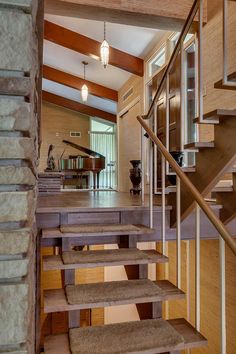 an open staircase leading up to a living room with piano on the far wall and stairs