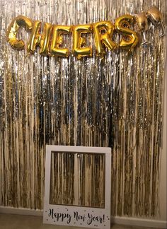 a photo frame sitting in front of a wall with foil streamers and the words cheers on it