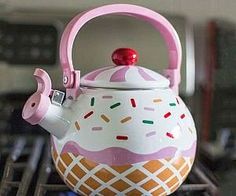 a tea pot with a pink handle and sprinkles on the inside is sitting on top of a stove