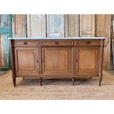 an old wooden sideboard with marble top in front of a door and rug on the floor