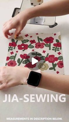 a woman is using an apple watch to sew flowers on a piece of fabric