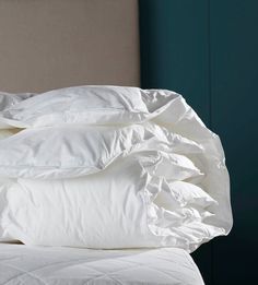 a pile of white pillows sitting on top of a bed