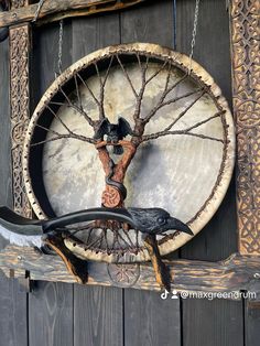 a bird is perched on the back of a wooden wall hanging with chains and an old tire wheel