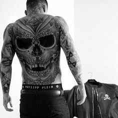 a man with tattoos standing next to a luggage bag