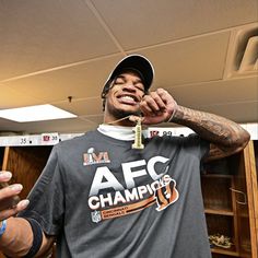 a man in a t - shirt and cap holding up a gold chain to his face