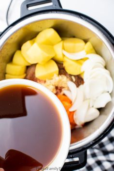 a person holding a cup with sauce in it next to a pot full of food