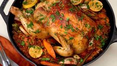 a roasted chicken in a pan with carrots and parsley garnishes