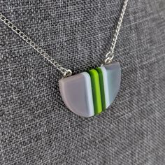 One of a kind handmade fused glass pendant. Simple and elegant modern minimalist style Transparent green gray and with stripes with geometric shape. Size: 30mm x 20mm x 6mm. Cast silver necklace attachments. Incorporates Bullseye opal and transparent glass. Sculpted by hand and fused multiple times. Includes nickle free hypoallergenic 18 inch attached chain. Message anytime with questions. -Sean Minimalist Green Glass Jewelry, Modern Green Geometric Jewelry, Modern Green Necklace As Gift, Modern Green Necklace For Gift, Modern Green Necklace As A Gift, Modern Green Round Pendant Jewelry, Minimalist Green Jewelry With Recycled Glass, Modern Green Round Pendant Necklace, Modern Green Necklace With Round Pendant