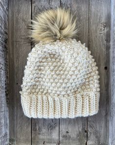 a white knitted hat with a fur pom