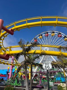 an amusement park with a ferris wheel, palm trees and blue sky in the background