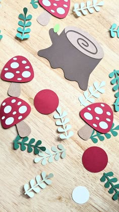 paper cut out mushrooms and leaves on a wooden surface