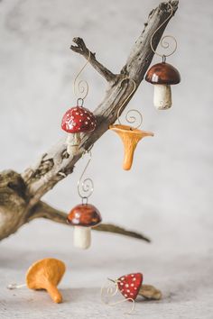 several mushrooms are hanging from a tree branch with metal ornaments attached to the branches in front of them