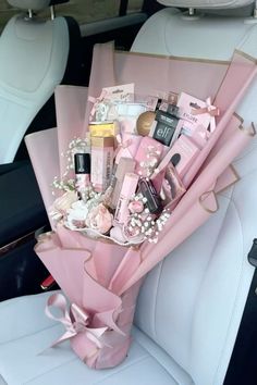 a pink bouquet sitting in the back seat of a car filled with makeup and cosmetics