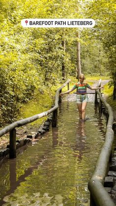 a woman is walking through the water on a path that has been dug into the ground