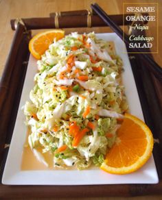 a white plate topped with coleslaw and oranges next to chopsticks