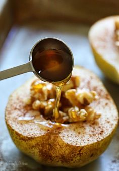 a spoon pouring caramel syrup on an apple cut in half with the peels still attached