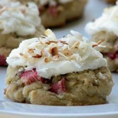 several desserts are sitting on a plate with white frosting and nuts all over them