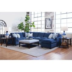 a living room with blue couches and pillows on the floor in front of a large window