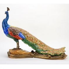 a figurine of a peacock sitting on top of a piece of gold and green