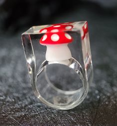 a glass ring with a red and white mushroom on it's side sitting on a table