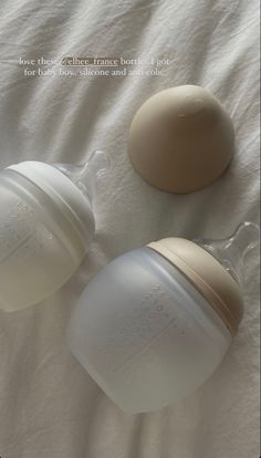 two baby bottles sitting next to each other on a bed