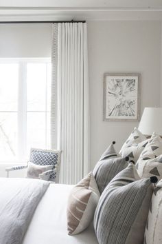 a bedroom with white walls and pillows on the bed