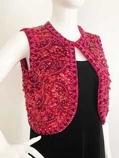 This is a beaded vest from Valentina, Ltd made in Hong Kong.  The beads are sewn to wool.  The lining feels like silk.  The front is thickly encrusted with a combination of sequins, beads and jewels.  There is an additional embellishment of pink pearls in an abstract design and along the edges.  The entire back is fully sequined with the same pearl trim as the front. One hook and eye closure. There is some damage to the lining, a small hole and a stain.  See pic.  This in no way interferes with the wearability of this vest.  Sturdy and ready to wear.  A few loose beads may be present.   Measurements taken with vest laying flat and doubled where appropriate. In order to determine fit we recommend comparing measurements to an item that fits you well. No stretch.  Length 16 inches Underarm to Fitted Embellished Vest, Elegant Embroidered Fitted Vest, Red Embroidered Sleeveless Vest, Elegant Fitted Embroidered Vest, Red Fitted Party Vest, Red Fitted Vest For Party, Beaded Vest, 2024 Wishlist, Long Sleeve Evening Gowns