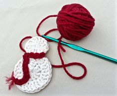 a crocheted snowman ornament next to a ball of yarn and a knitting needle