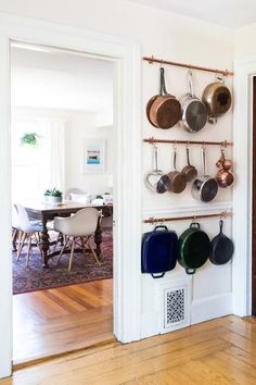 pots and pans are hanging on the wall next to a dining room table with chairs