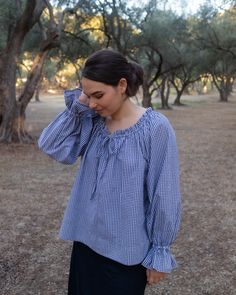 a woman in a blue and white checkered top is talking on her cell phone