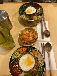 three bowls of food on a table with chopsticks and spoons next to them