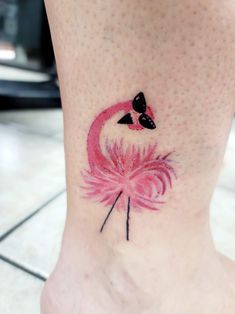 a pink flamingo tattoo on the ankle with black dots around it's eyes