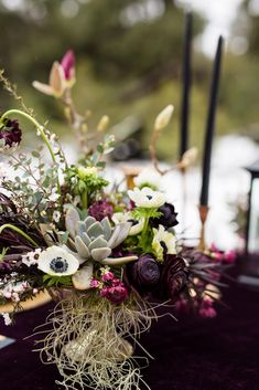 an arrangement of flowers and succulents on a purple table cloth at a wedding