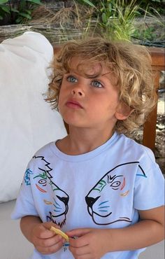 a little boy that is standing in front of a pillow and eating something with his hands