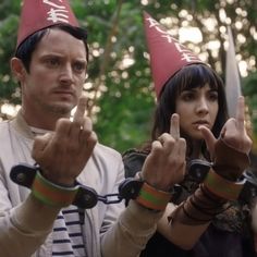 two people dressed up as gnomes with their hands in the air and pointing at something