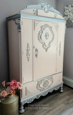 a white armoire sitting next to a vase with flowers