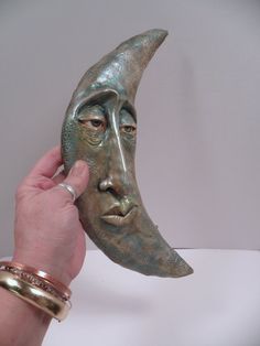 a person holding up a green mask with a face on it