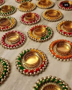 many different colored and gold plated items on a white tablecloth with beads around the edges