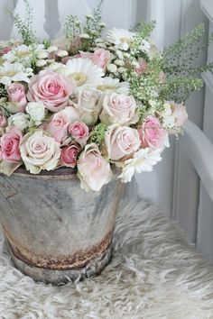 a bucket filled with lots of pink and white flowers on top of a fur covered floor