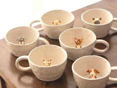 six white cups with dogs in them sitting on a wooden table top next to each other