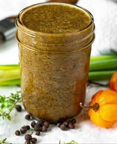 a jar filled with some kind of food on top of a white table next to vegetables