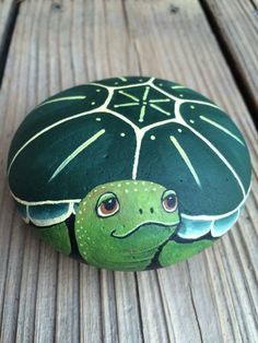 a painted turtle sitting on top of a wooden floor next to a green umbrella shaped rock