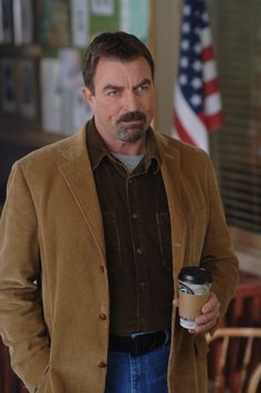 a man with a mustache holding a coffee cup