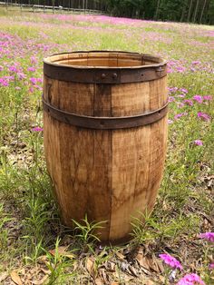 a wooden barrel sitting in the middle of a field full of purple flowers and grass