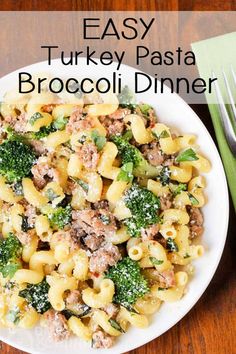 a white plate topped with pasta and broccoli covered in sauce next to a fork