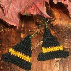 two crocheted black and yellow triangle shaped earrings sitting on top of a wooden table