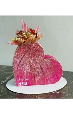 a pink vase filled with flowers on top of a white plate next to a wall